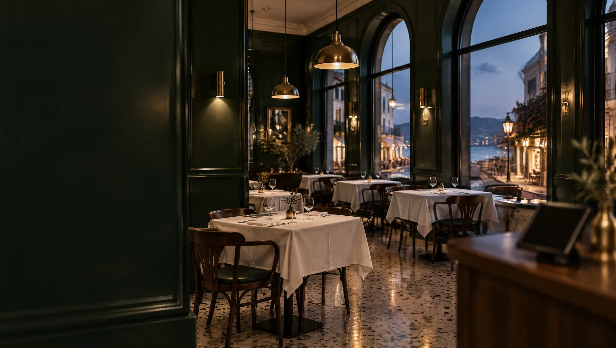 Akşam servisinden önce koyu yeşil duvarlı, pirinç lambalı bir restoran salonu
